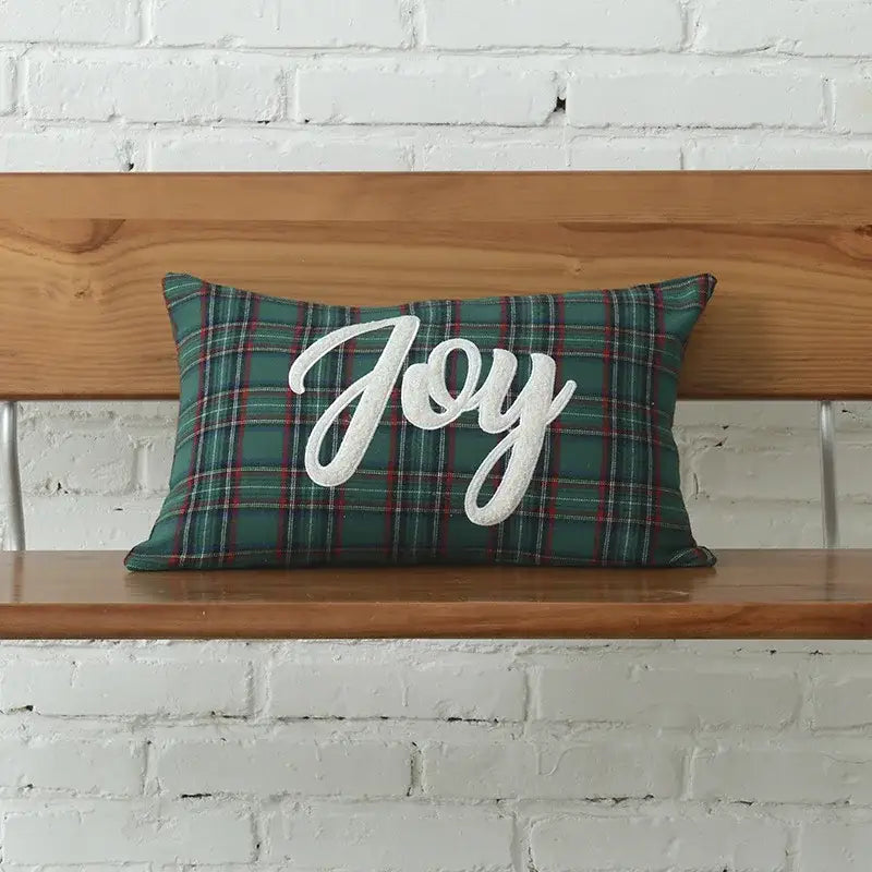A rectangular green plaid pillow with white cursive christmas letter embroidery spelling joy from decorbites christmas letter set