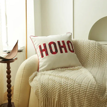 White cushion with red ho ho christmas letter embroidery in plaid pattern and red stitched border from decorbites christmas letter set