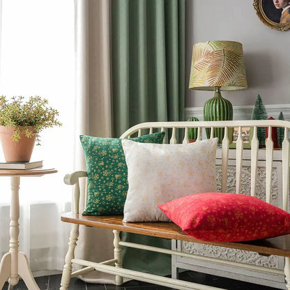 Three decorative decorbites christmas plaid cushion covers in green cream and red with floral patterns on wooden bench