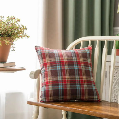 Red brown and blue plaid decorbites christmas plaid cushion cover resting on a wooden bench for holiday decor