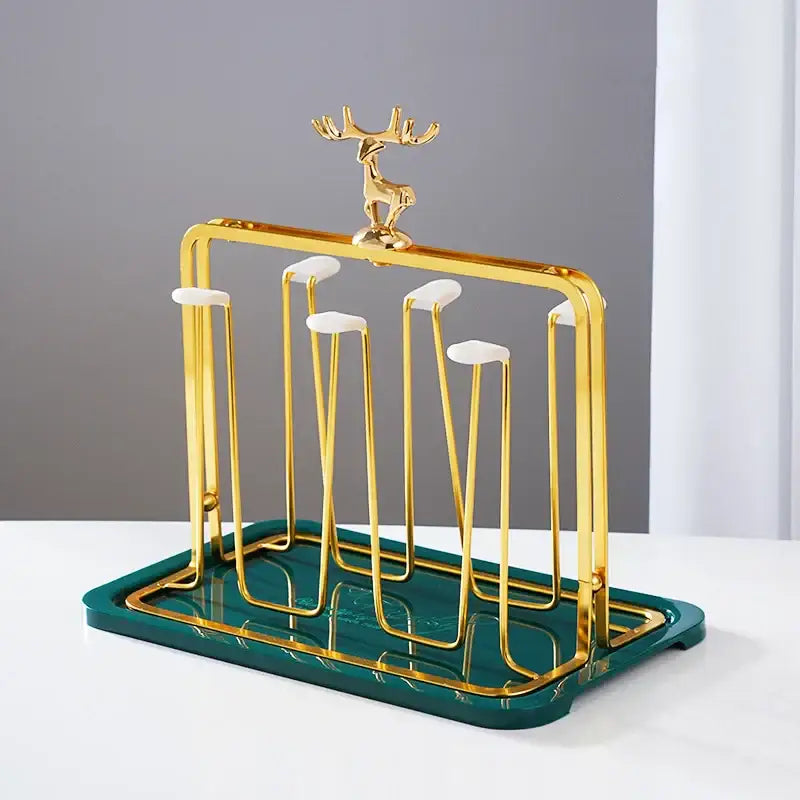 Gold metal cups holder set with deer figurine and white ceramic accents on dark green tray for drying cups