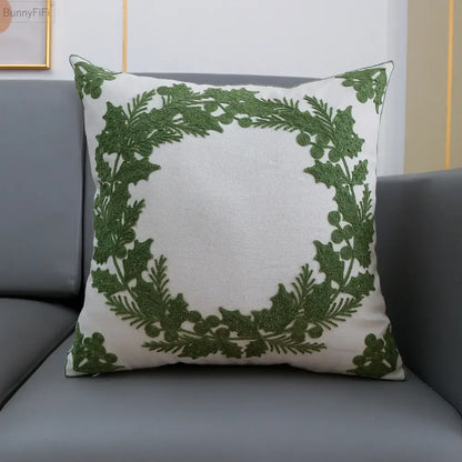 White cushion cover featuring an embroidered green holly wreath design by decorbites christmas snowflake collection