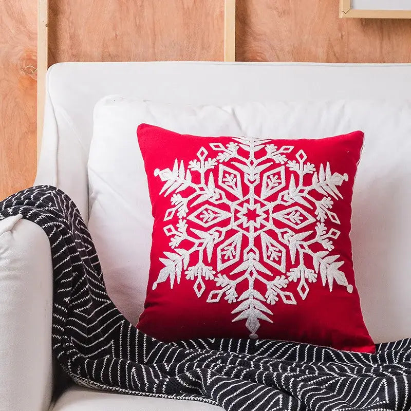 Red velvet throw pillow with intricate white embroidered snowflake design from decorbites christmas snowflake elk collection