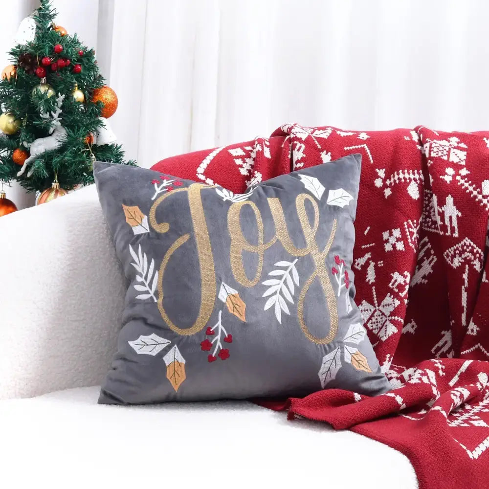 Gray velvet cushion cover with embroidered gold joy lettering and christmas tree leafy accents for festive decor