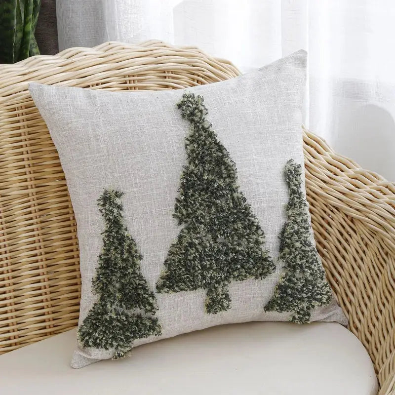 A light beige linen pillow cover with three textured green pine tree appliqués from decorbites christmas tree gold collection