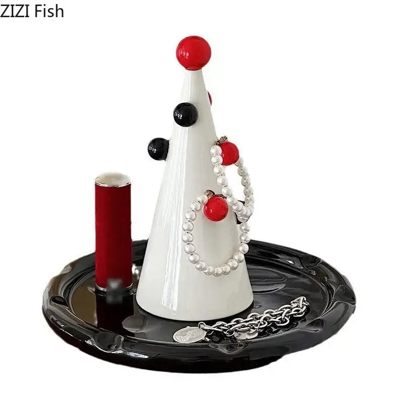 White ceramic christmas tree jewelry stand by DecorBites holding pearl necklaces and silver chains with red and black ornaments