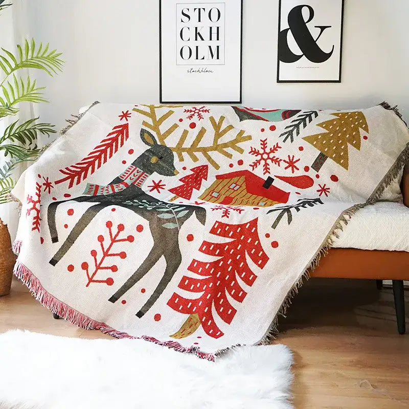 A cozy cream-colored decorbites christmas tree knitted throw blanket featuring a festive winter scene with deer and trees