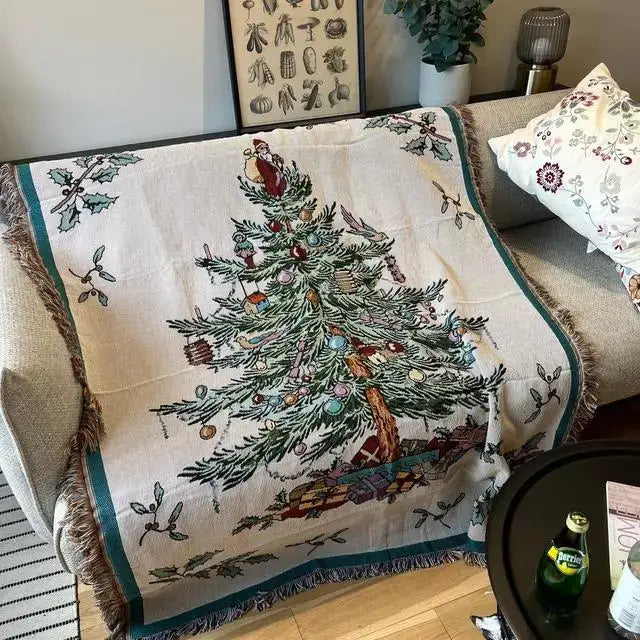 A cream-colored decorbites christmas tree knitted throw blanket with detailed tree design and fringed holly edges