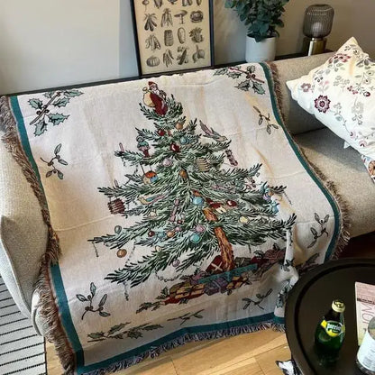 A cream-colored decorbites christmas tree knitted throw blanket with detailed tree design and fringed holly edges
