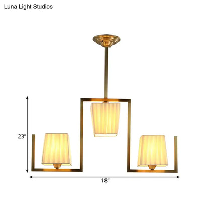 Gold-toned rectangular chandelier light kit with three warm pleated fabric shades for dining room ceiling light