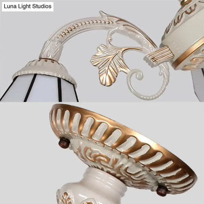 White and gold ornate ceramic wall sconce with leaf scrollwork detailing for a multi light chandelier ceiling light with white glass