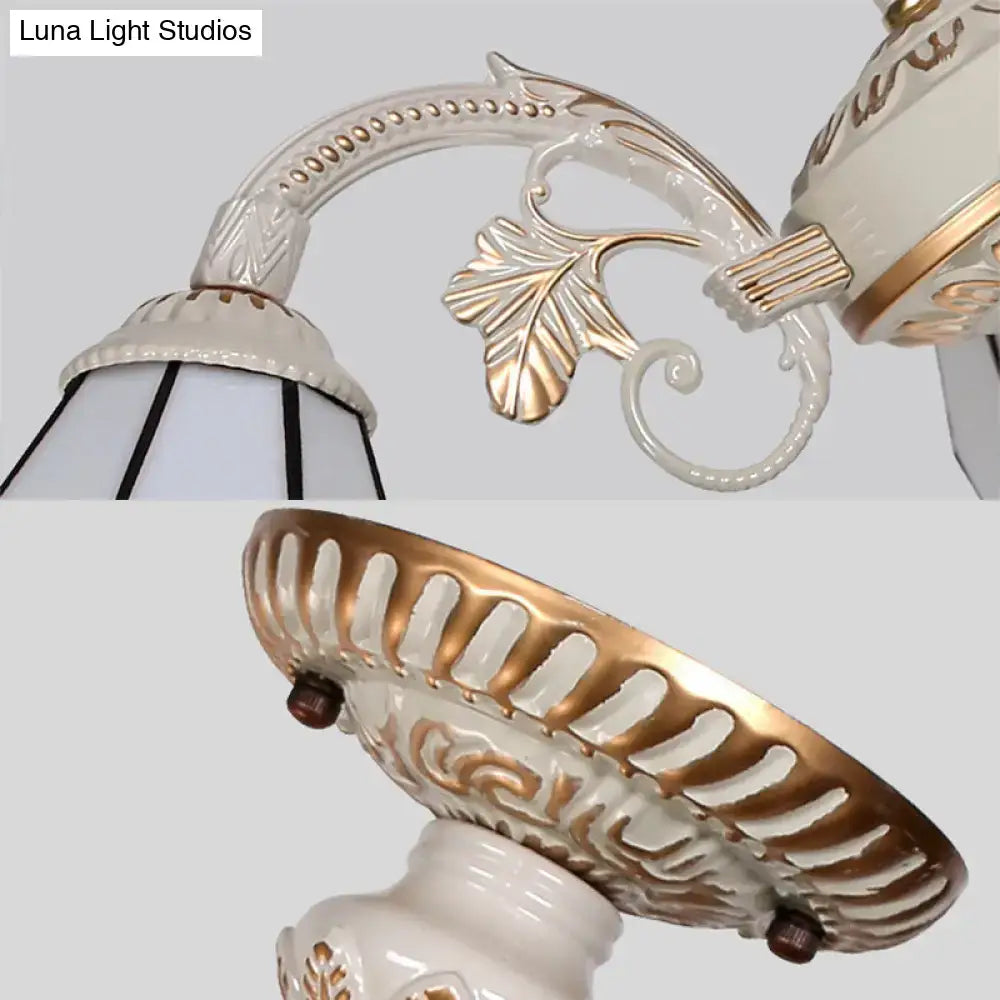 Antique-style porcelain wall sconce with gold leaf accents and floral detailing complementing a multi light chandelier