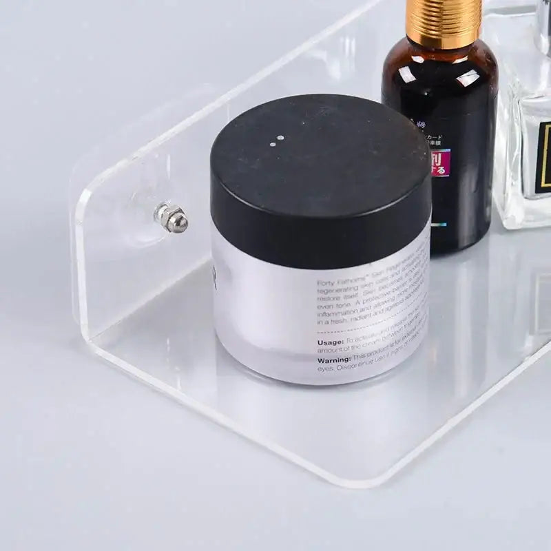 Clear acrylic wall mounted shelf organizer holding a black-lidded white jar of forty palms skincare product