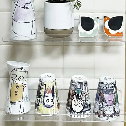 Decorbites™ clear acrylic wall mounted shelf organizer holding whimsical white ceramic vases with colorful illustrations