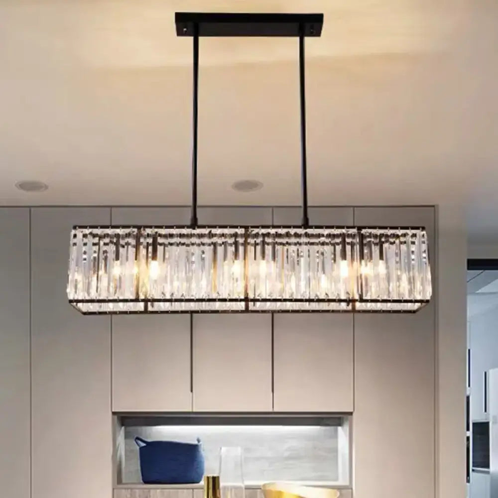A decorbites clear crystal island pendant light with black metal frame and hanging crystal rods refracting warm light