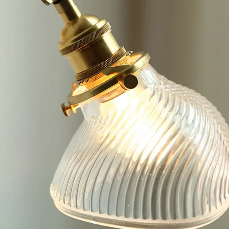 A warm-glowing decorbites clear glass led brass wall sconce with a ribbed glass shade for dining room lighting