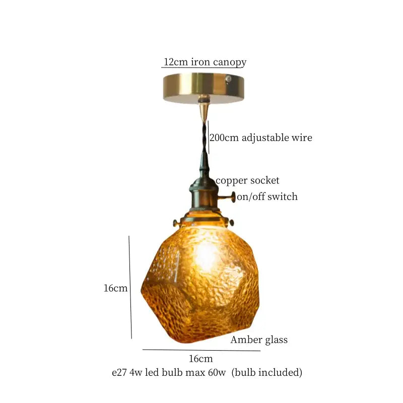 A warm amber decorbites clear glass led pendant light with textured faceted surface and brass hardware for bedroom