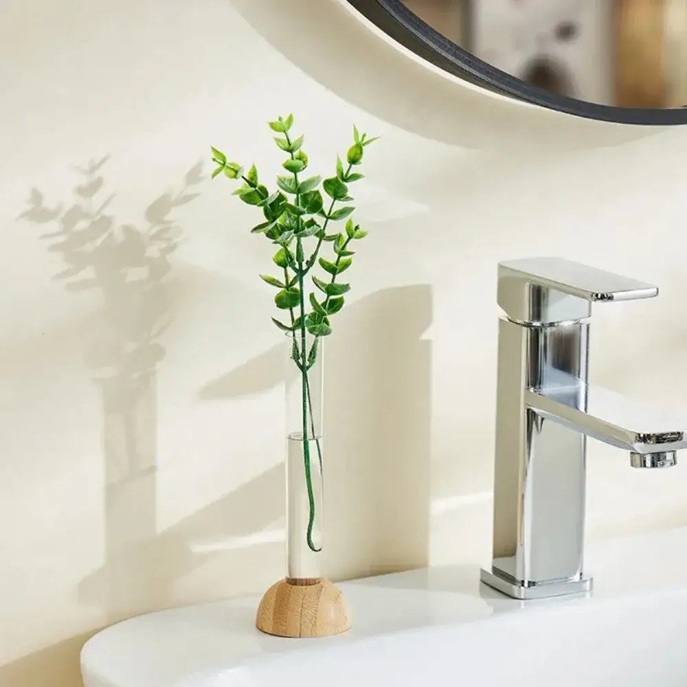 DecorBites™ clear vase with bamboo base holding vibrant green eucalyptus sprigs as a hydroponic vase tabletop decoration