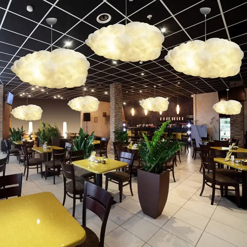 Soft glowing white cotton decorbites cloud chandelier pendant lights hang from a dark ceiling grid for bedroom use