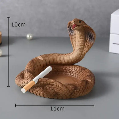 Brown decorbites cobra ashtray in orange resin with detailed scales and open mouth holding cigarette in coiled body