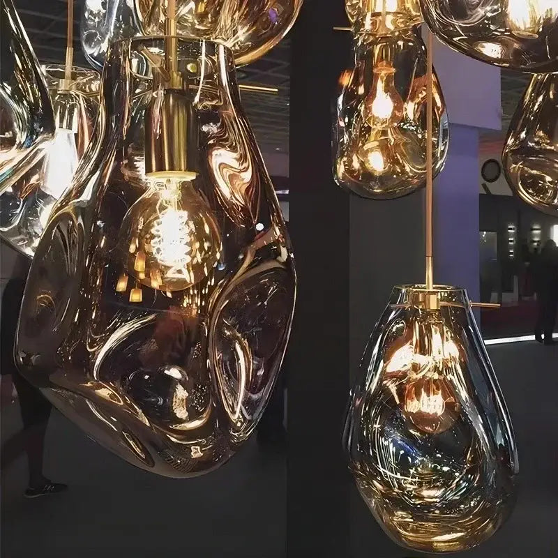 Golden fluidly shaped glass pendant light with brass accents and exposed filament bulbs in decorbites colorful glass chandelier