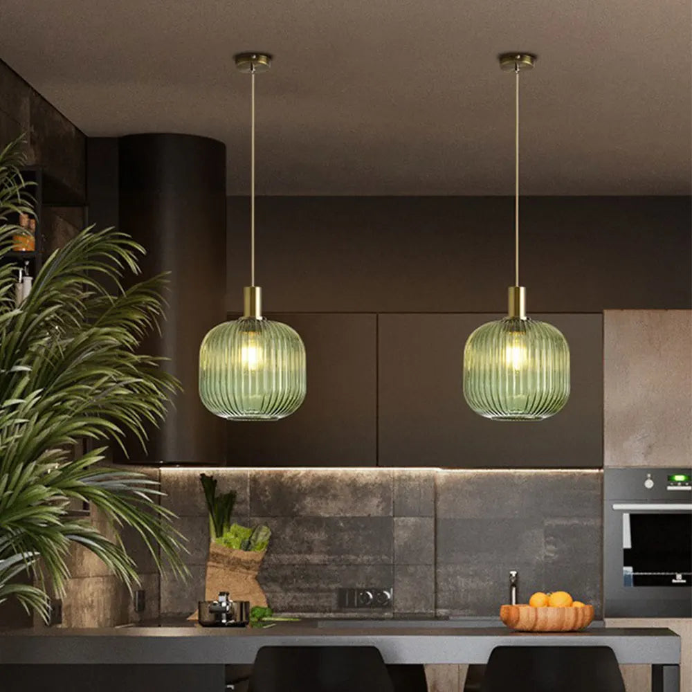 Two identical green ribbed glass pendant lights with brass fixtures hang from the ceiling for retro style decor