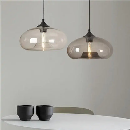 Two modern decorbites™ colorful led glass pendant lights with frosted shades hang above a white restaurant table