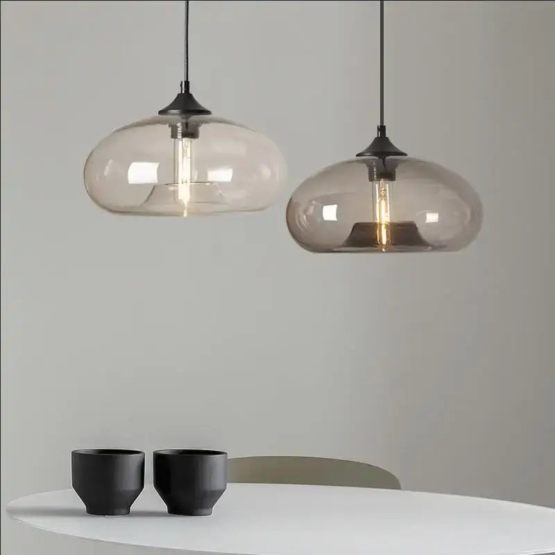 Two modern decorbites™ colorful led glass pendant lights with frosted shades hang above a white restaurant table