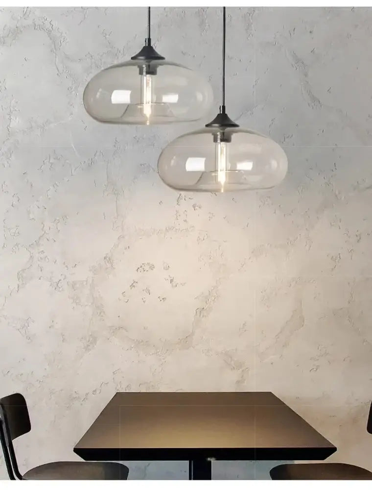 Two colorful led glass pendant lights with black metal fixtures hang above a dark wooden restaurant table