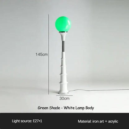 A sleek white floor lamp with a glowing green spherical shade and iron art base from decorbites colorful memphis collection