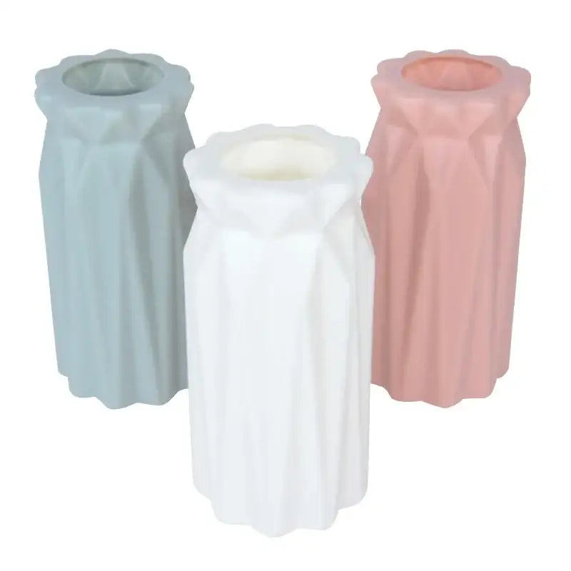 Set of three pastel-colored colorful plastic flower vases in blue white and pink with faceted surfaces for home décor