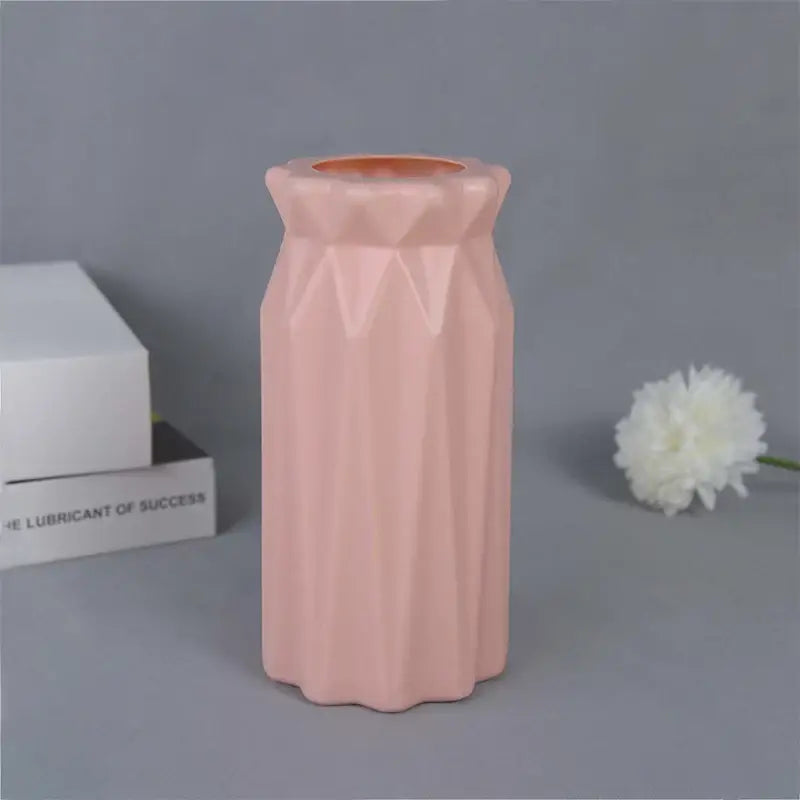 A sleek matte pink ceramic flower vase with geometric facets and flared rim for modern home décor by decorbites™
