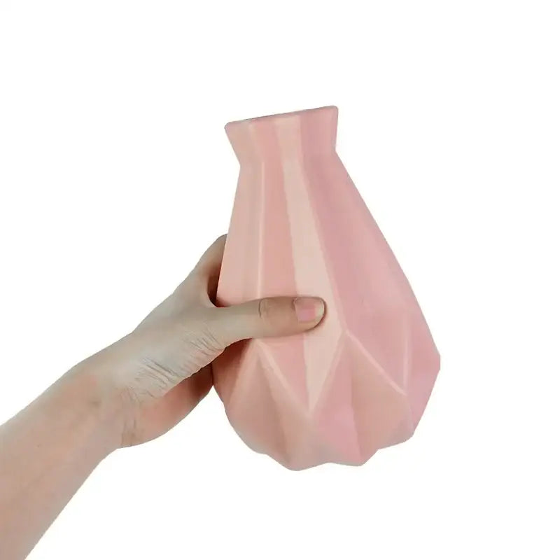 A soft pink modern flower vase by decorbites with a geometrically faceted design for colorful plastic flower display