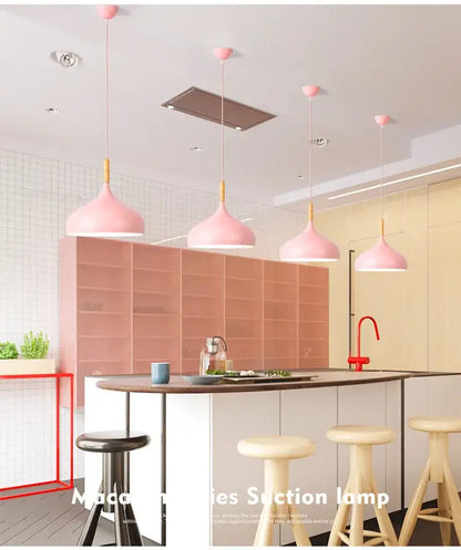 Pink colorful retro pendant lights with gold-toned fixtures hang from the ceiling for stylish home decor
