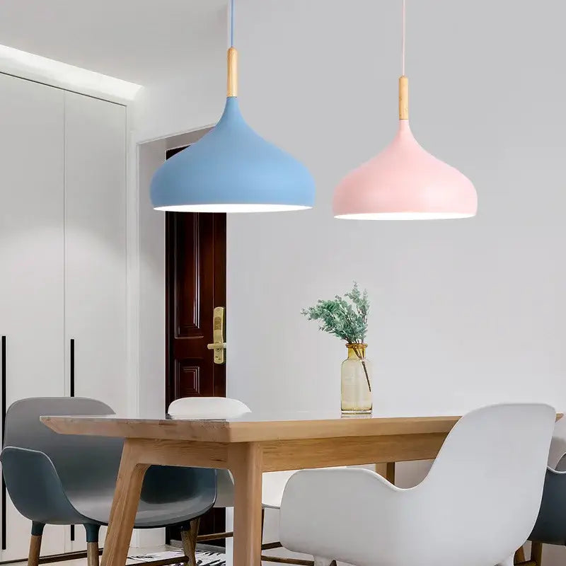 Two colorful retro pendant lights with matte blue and pink shades and wooden accents for home decor by DecorBites
