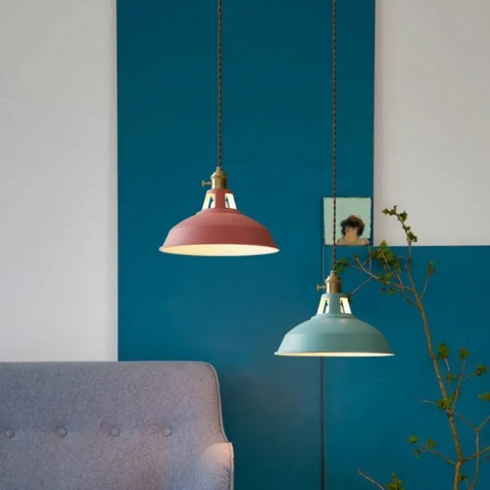 Two colorful retro pendant lights with matte metal shades in red and teal hang against a bold blue wall