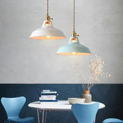 Two colorful retro pendant lights with white and light blue enamel shades brass hardware and twisted cords