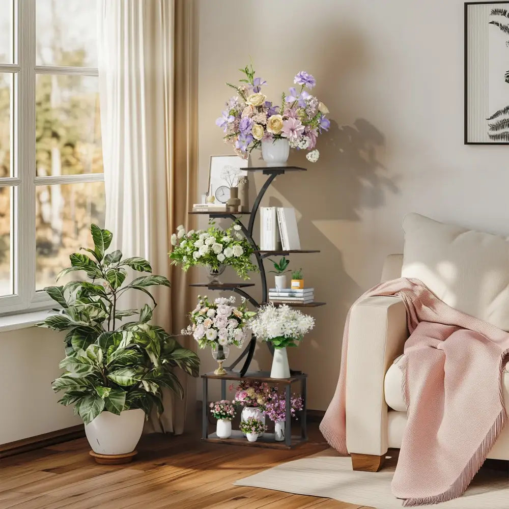 Black metal plant stand with multiple curved shelves holding floral arrangements and books in compact tree design