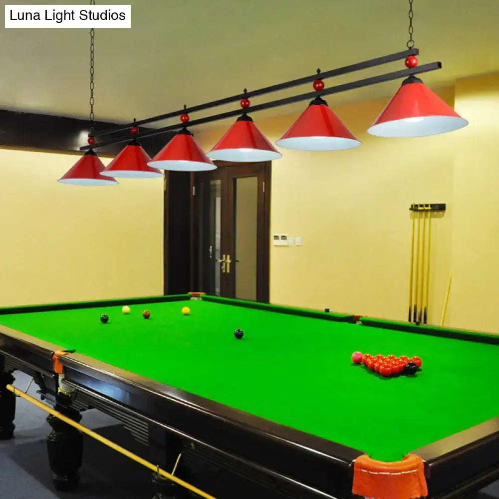 Red conical metal pendant ceiling lights with white interiors hang above a pool table in industrial style decor