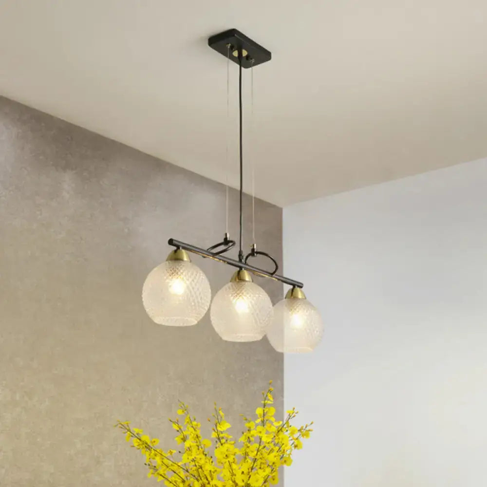 Modern black metal pendant light with three frosted globe shades featuring clear prismatic glass for dining hall use