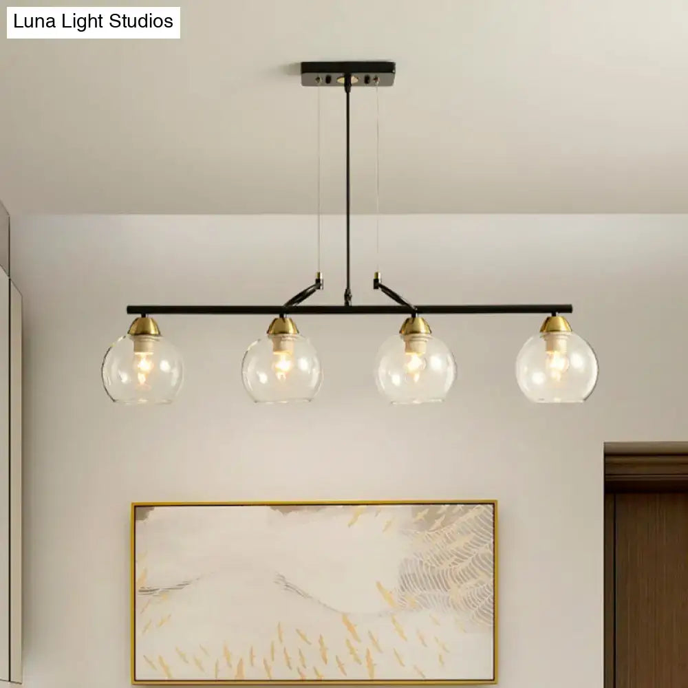 Black metal bar pendant light with four clear prismatic glass globe shades and brass accents for dining hall use
