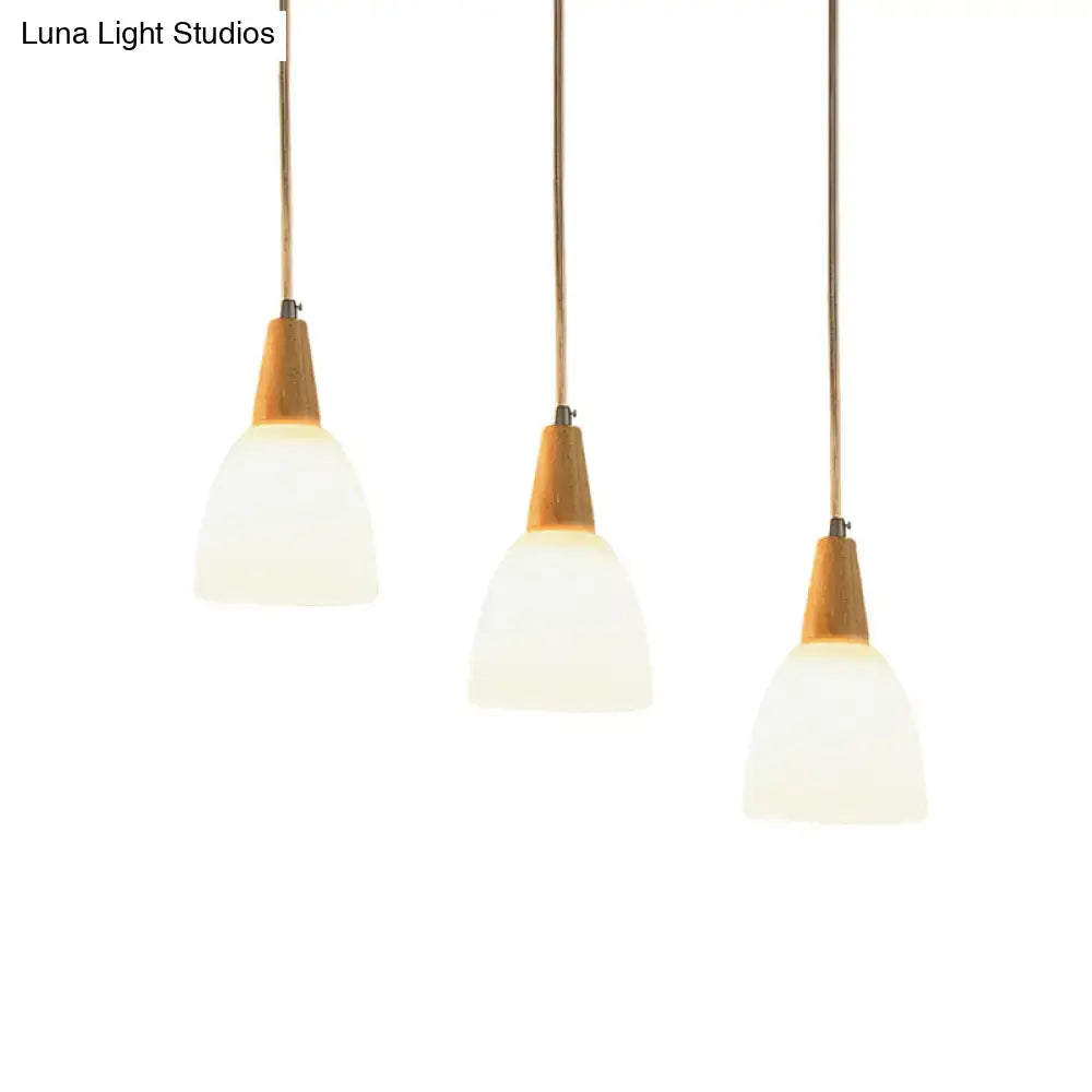 Three beige decorbites™ pendant lights with frosted glass dome shades and wooden tops suspended by brass cords