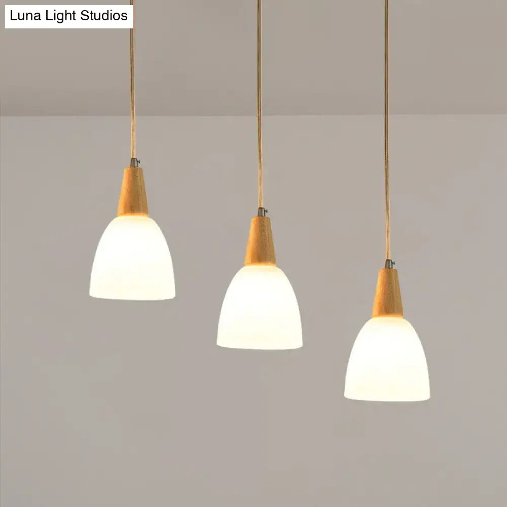 Three modern decorbites™ pendant lights with warm wood tops and frosted glass dome shades suspended by cords