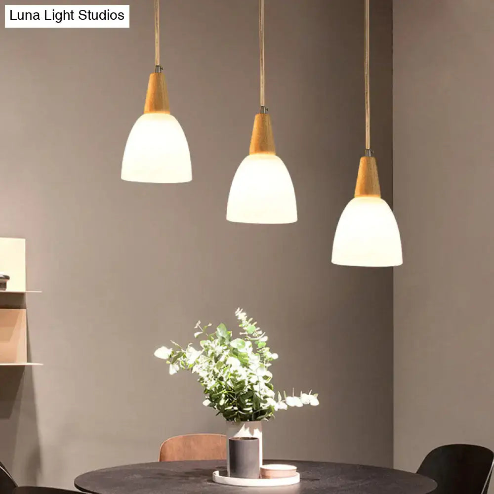 Three modern decorbites frosted glass dome pendant lights with beige glass domes and warm wood tops hanging by brass cords