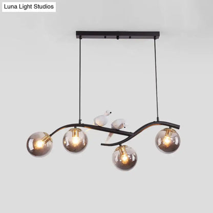 Black metal chandelier with five smoke grey glass globes and white bird decor on curved arms from DecorBites™