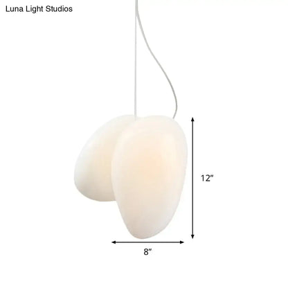 Cream-colored decorbites™ contemporary white glass pendant light with organic oval shape and white glass stacked cord suspension