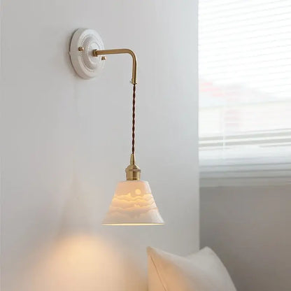Off-white ceramic wall lamp with mountain etching suspended by twisted bronze cord on decorbites copper arm vintage fixture