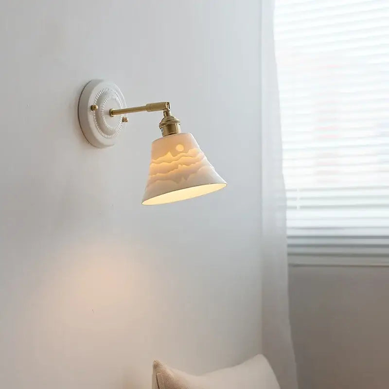 Cream-colored ceramic wall lamp with brass-finished copper arm vintage design by decorbites for bedroom lighting