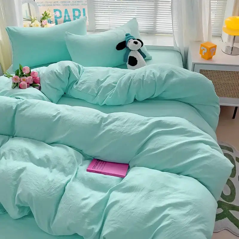 Mint green cotton bedding set with duvet cover and pillowcases featuring a plush stuffed dog on bed by DecorBites