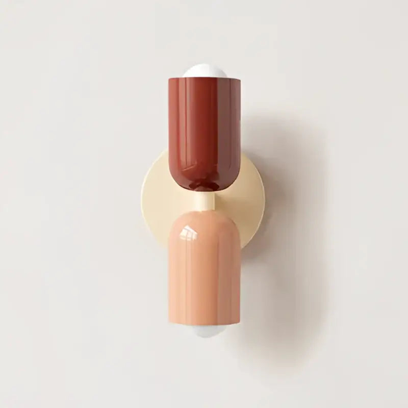 A modern two-toned wall lamp with cream double head featuring glossy terracotta and matte peach on brass backplate